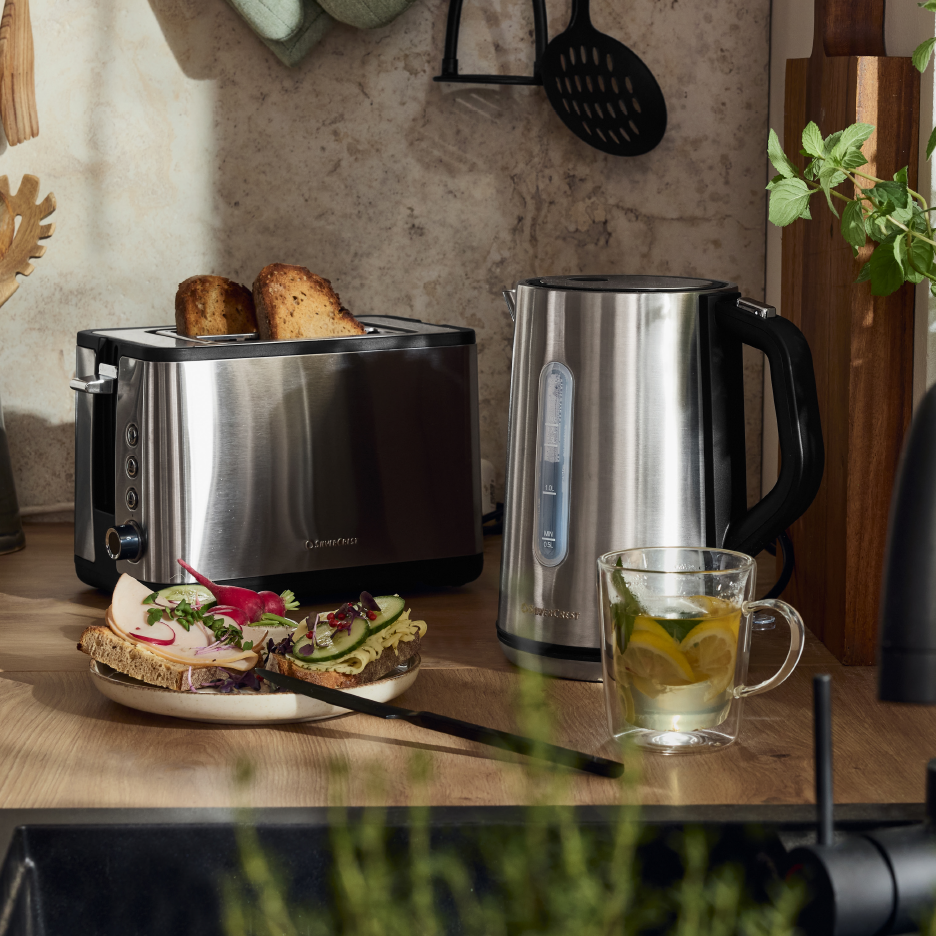 Ανοξείδωτη τοστιέρα και βραστήρας Silvercrest σε πάγκο κουζίνας με σάντουιτς και τσάι.