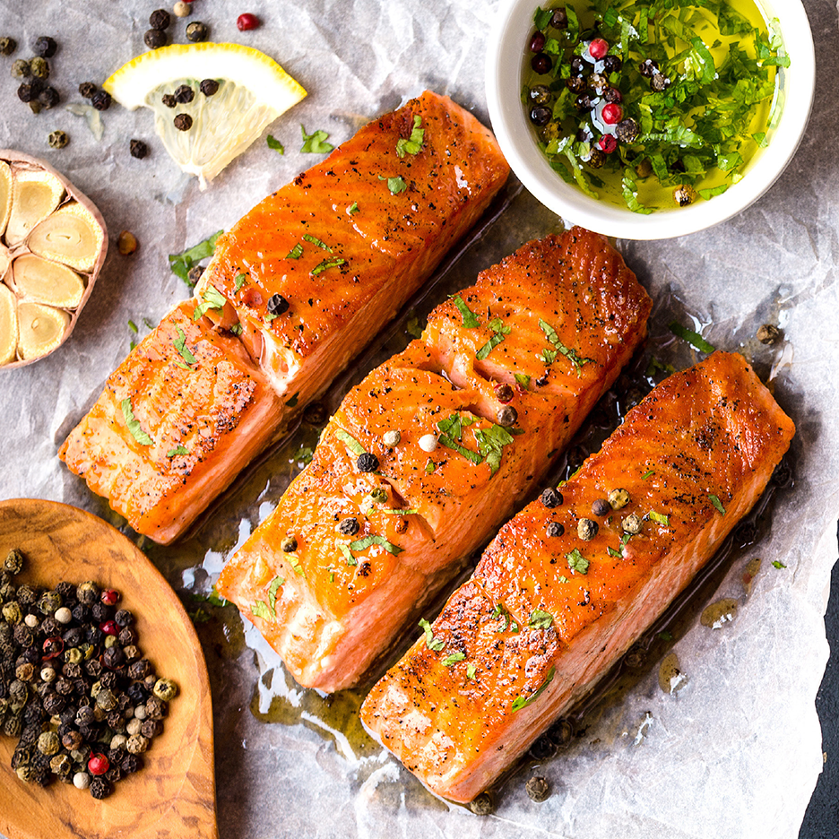 Τρία φιλέτα σολομού με βότανα, πιπέρι, σκόρδο και λεμόνι σε λαδόκολλα.