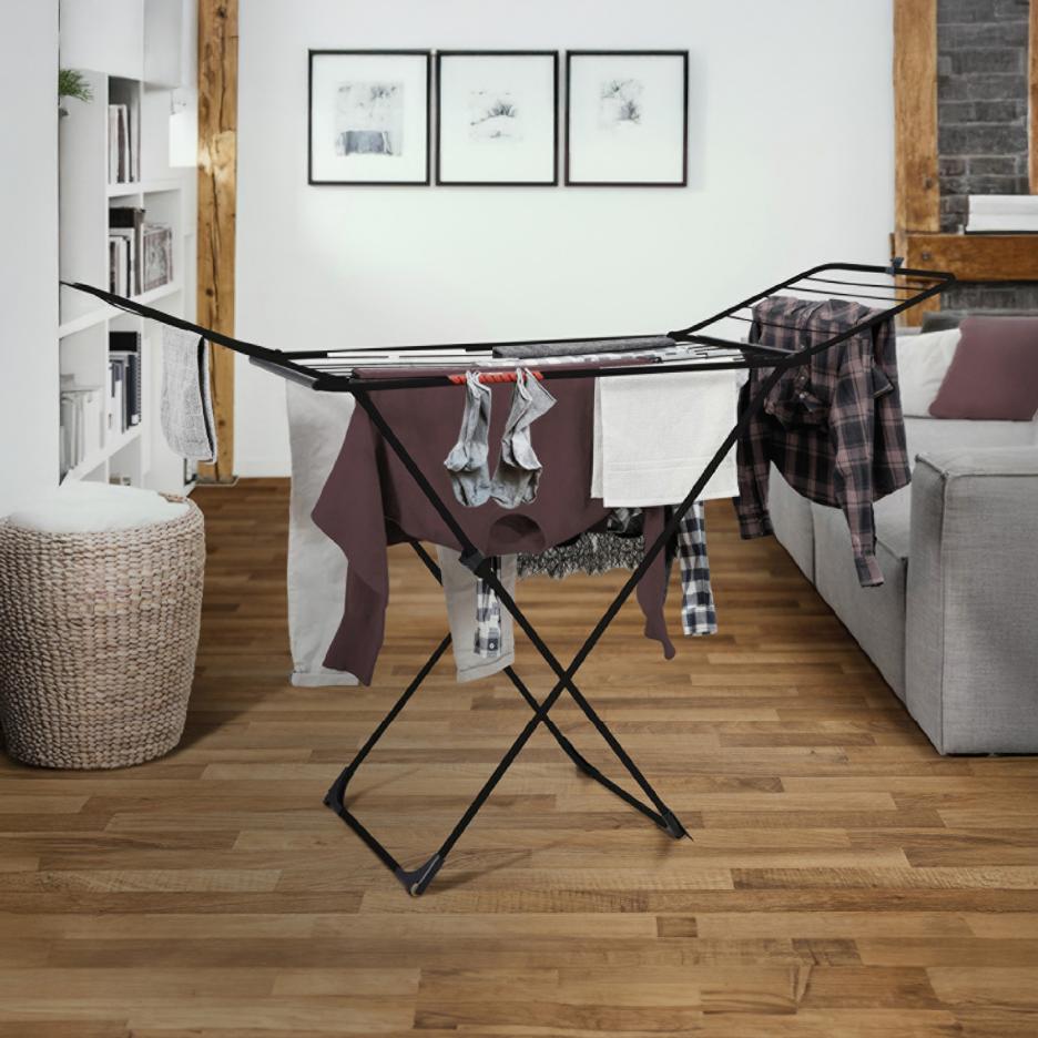 Μαύρη απλώστρα ρούχων με απλωμένα ρούχα σε ένα μοντέρνο σαλόνι.