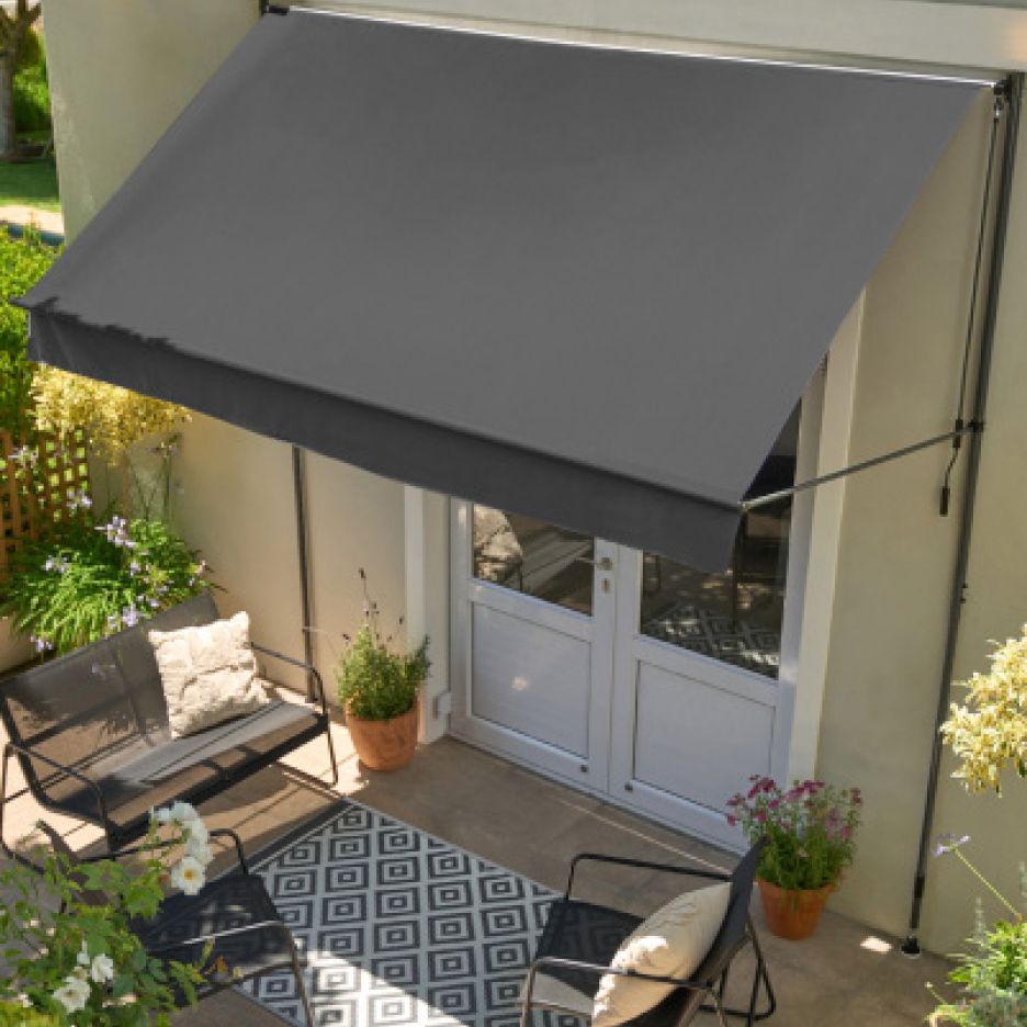 Γκρι τέντα πάνω από βεράντα με έπιπλα εξωτερικού χώρου και φυτά.