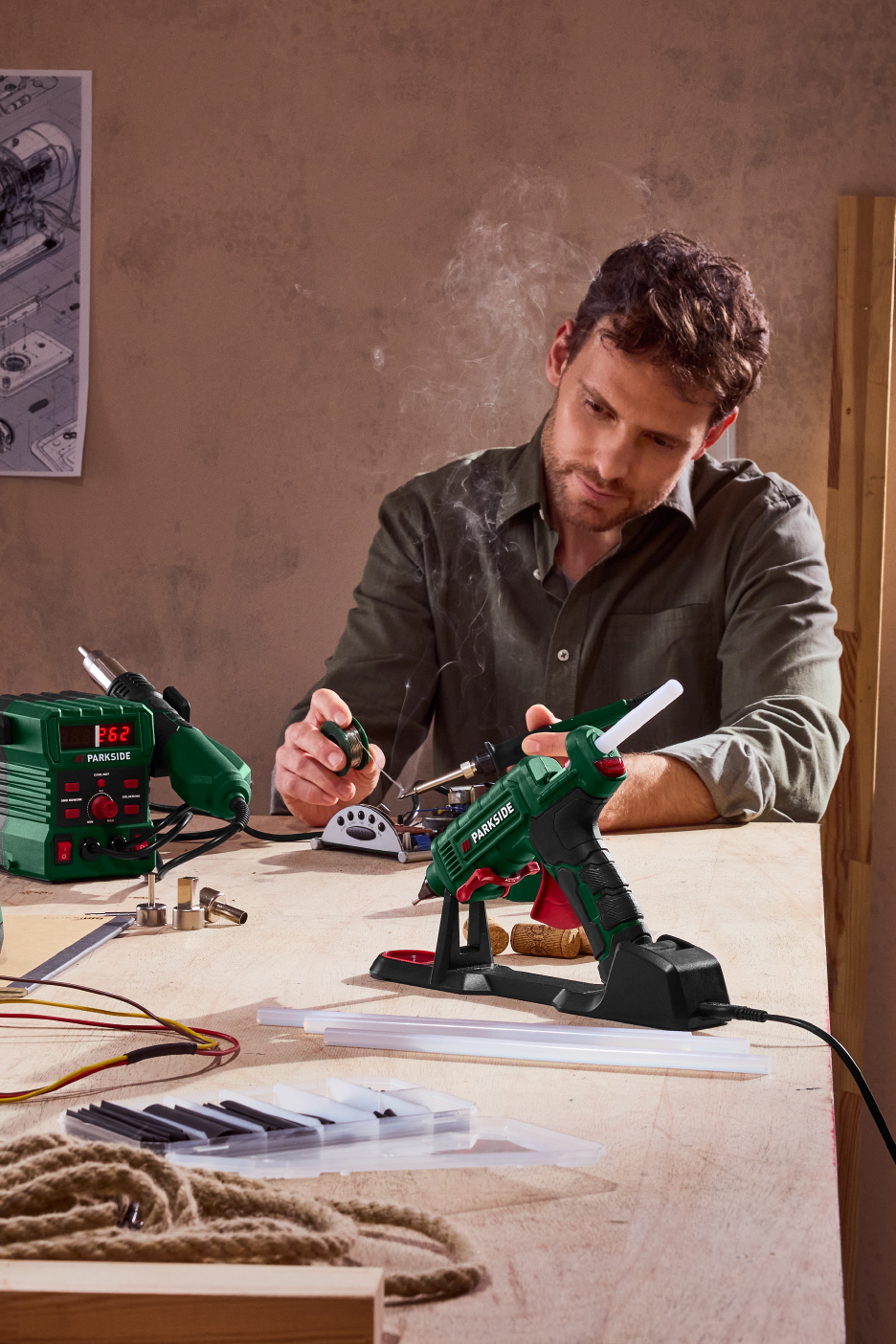 Άντρας χρησιμοποιεί πιστόλι θερμοκόλλησης Parkside, με πιστόλι θερμού αέρα και σταθμό συγκόλλησης.