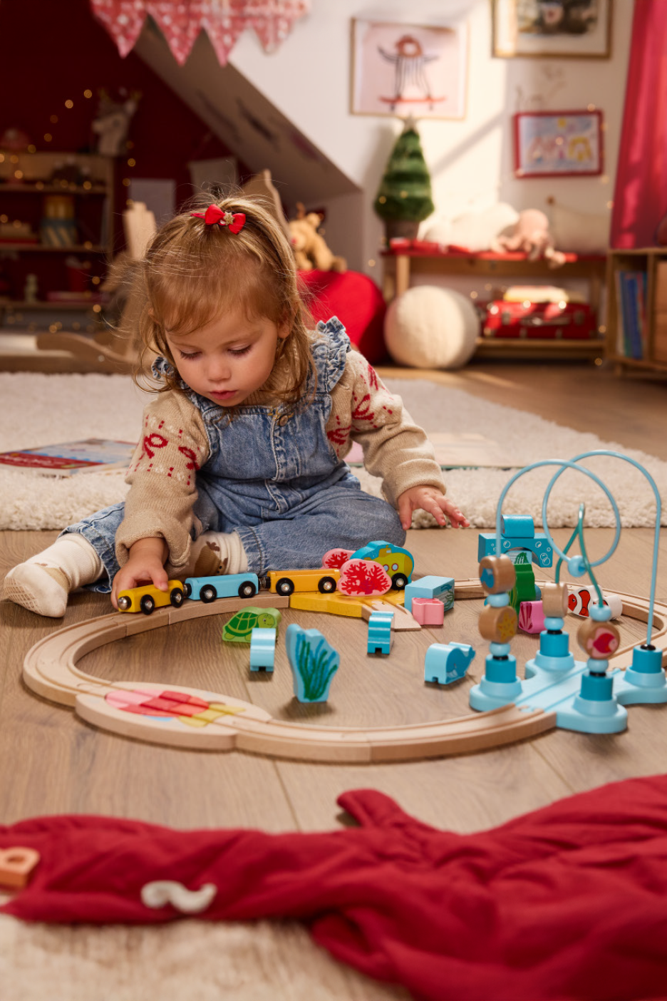 Μικρό παιδί παίζει με ξύλινο τρένο και παιχνίδια δραστηριοτήτων σε χαλί.
