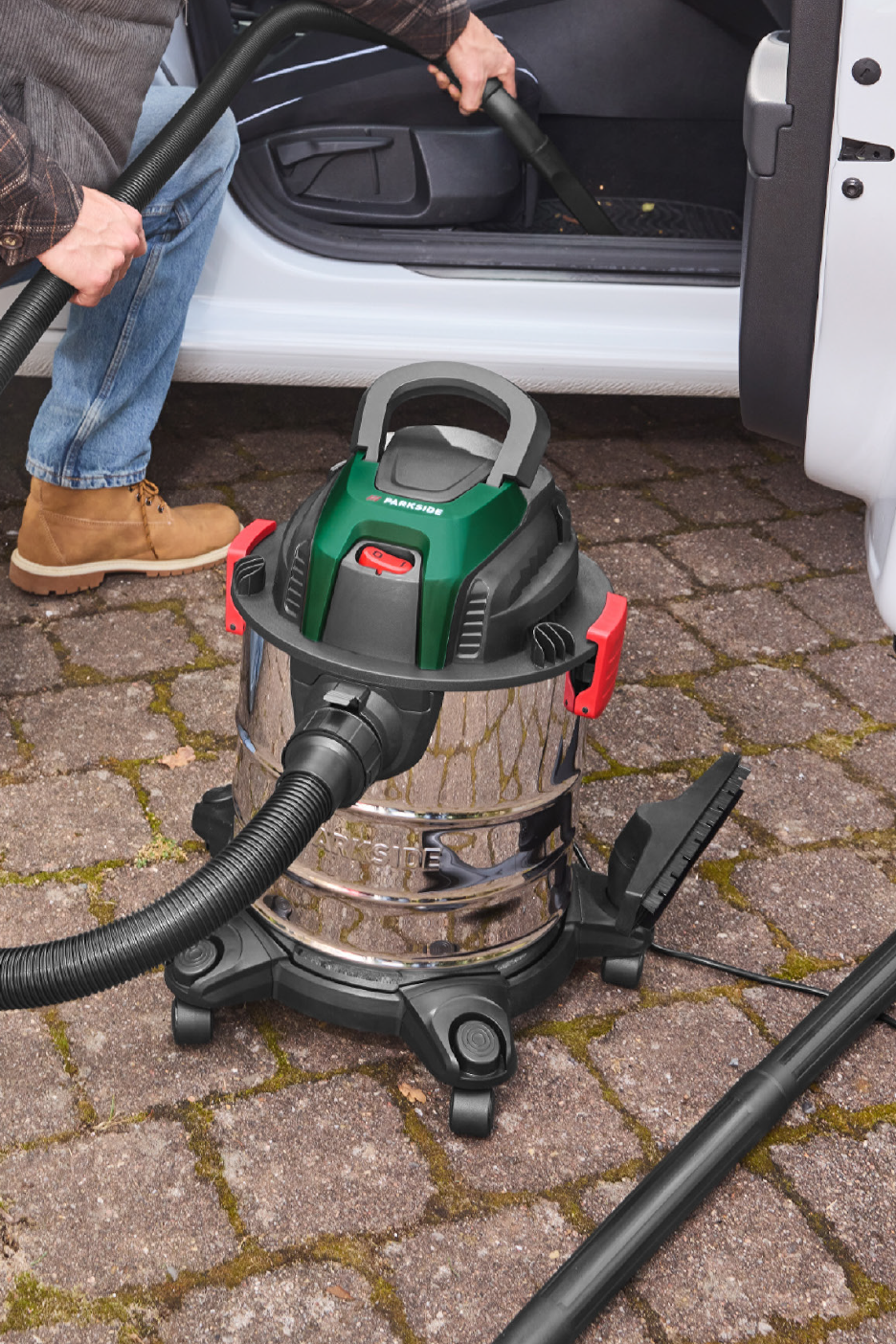 Άνδρας καθαρίζει το εσωτερικό του αυτοκινήτου με ηλεκτρική σκούπα υγρής και ξηρής αναρρόφησης.