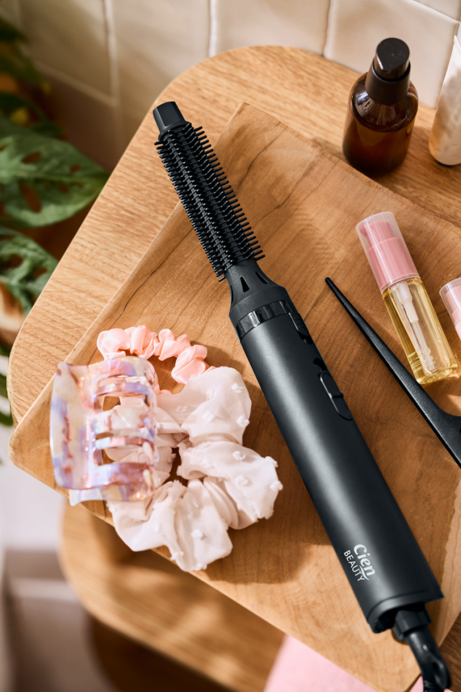 Μαύρη βούρτσα μαλλιών με ζώνη, scrunchies και προϊόντα περιποίησης μαλλιών σε ξύλινο δίσκο.