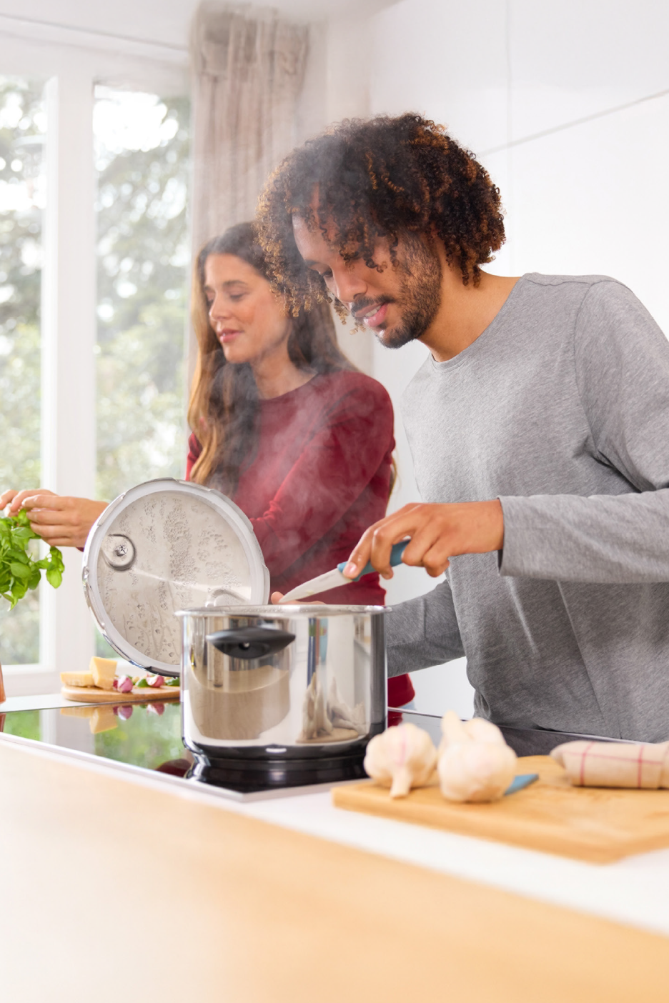 Ένα ζευγάρι μαγειρεύει σε μια κουζίνα, με μια κατσαρόλα να βράζει στον πάγκο.