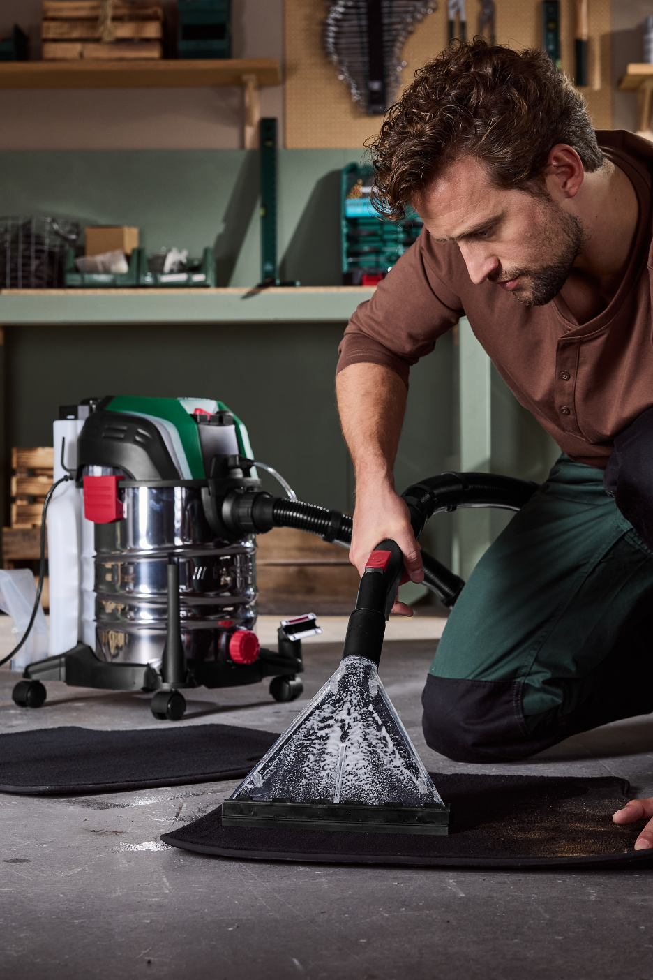 Άντρας καθαρίζει πατάκι αυτοκινήτου με ηλεκτρική σκούπα υγρών και στερεών.