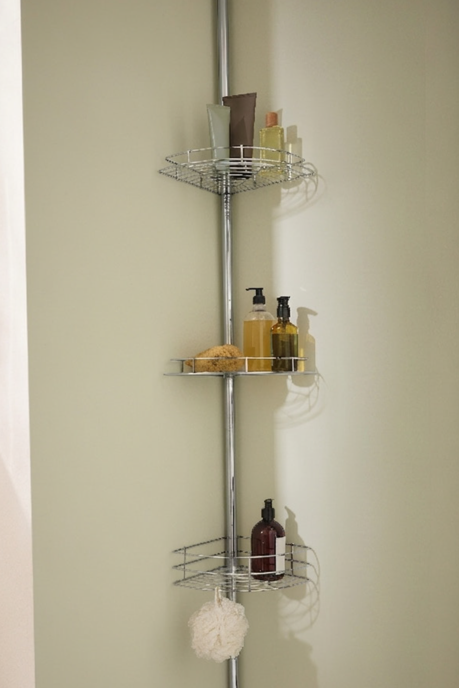 Μεταλλική γωνιακή ραφιέρα ντους με σαπούνια, σφουγγάρι και προϊόντα περιποίησης.