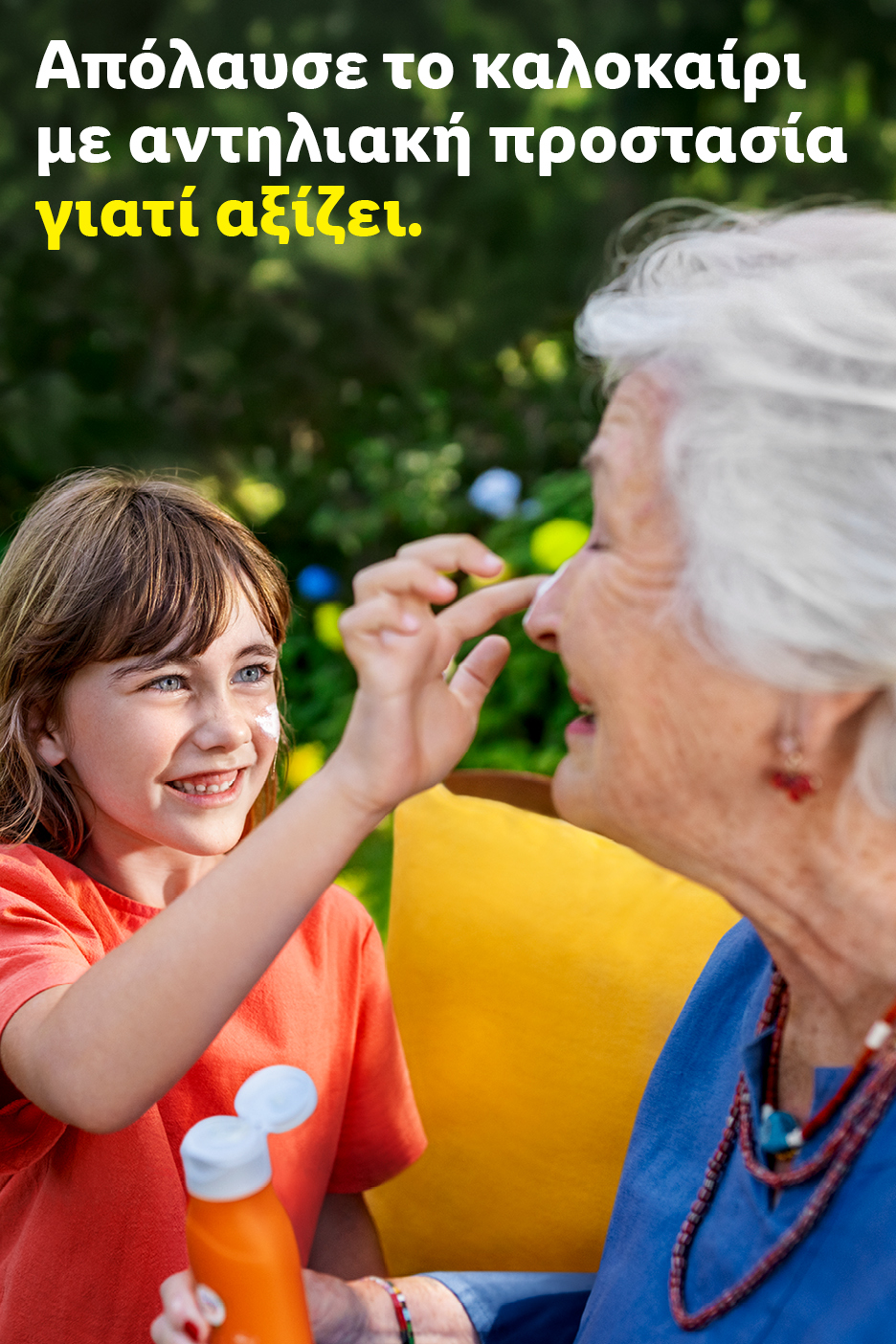Κορίτσι απλώνει αντηλιακό σε ηλικιωμένη γυναίκα. Κείμενο: «Απόλαυσε το καλοκαίρι με αντηλιακή προστασία γιατί αξίζει».