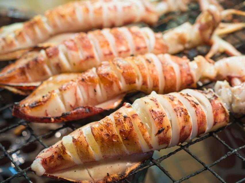 Ψητά καλαμάρια κομμένα σε φέτες πάνω σε σχάρα.