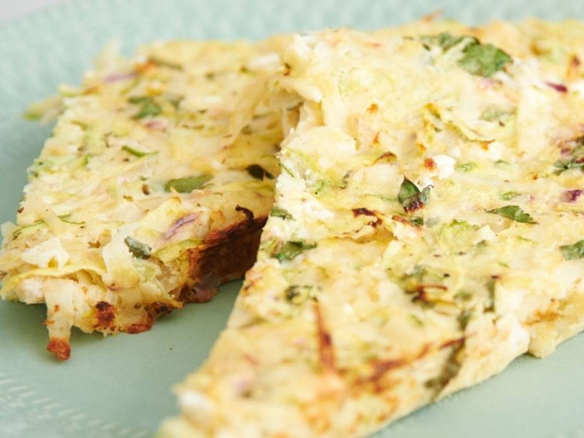 Δύο κομμάτια ομελέτας με λαχανικά και μυρωδικά σε γαλάζιο πιάτο.