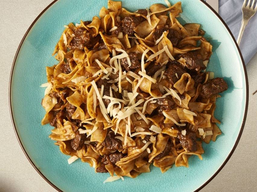 Ζυμαρικά με μοσχάρι και τυρί σε τιρκουάζ πιάτο.