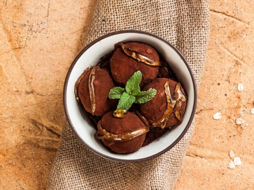 Σοκολατένιες τρούφες με μέντα και σιρόπι σε μπολ, πάνω σε λινάτσα και ξύλο.