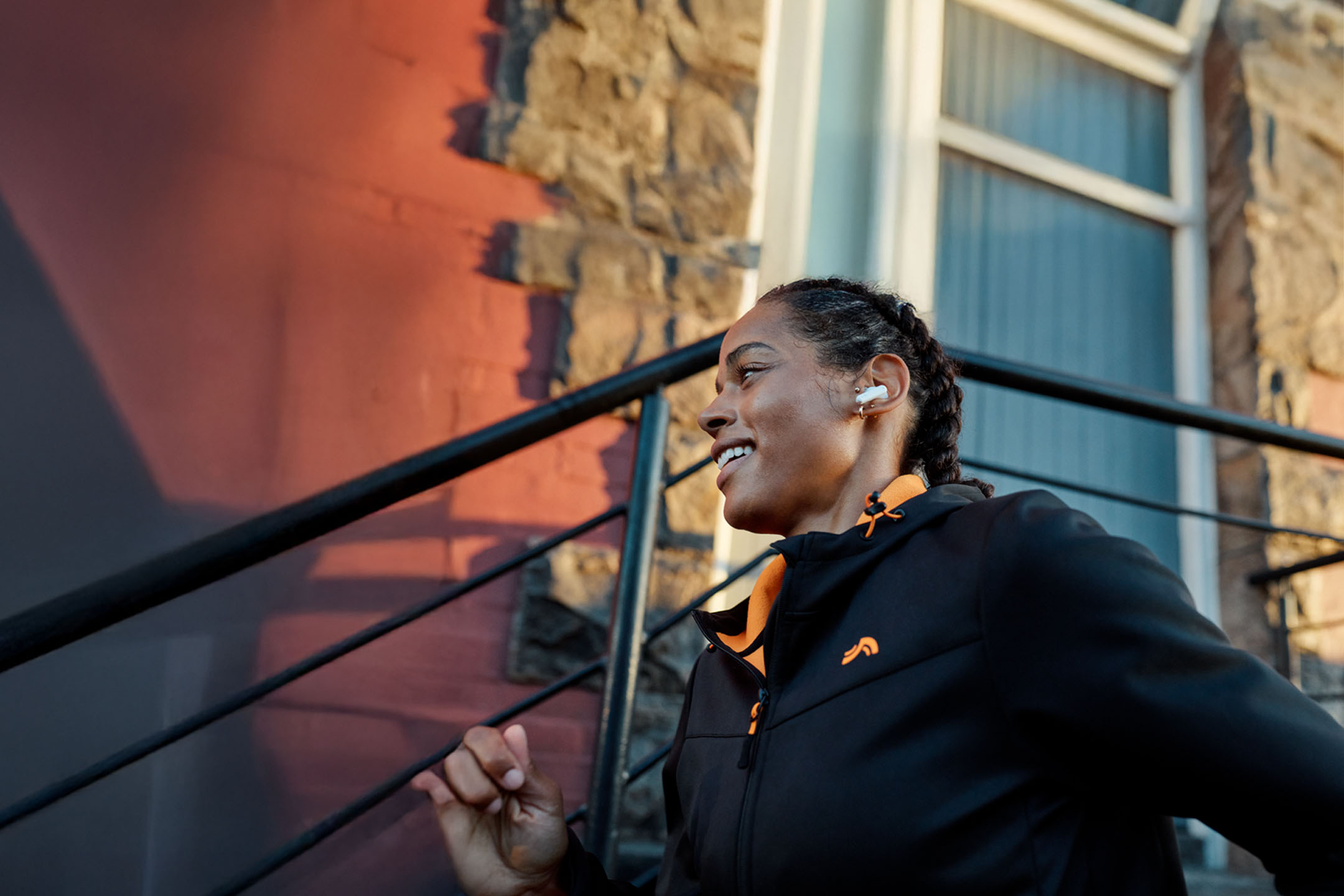 Γυναίκα τρέχει με ακουστικά, φορώντας μπουφάν.